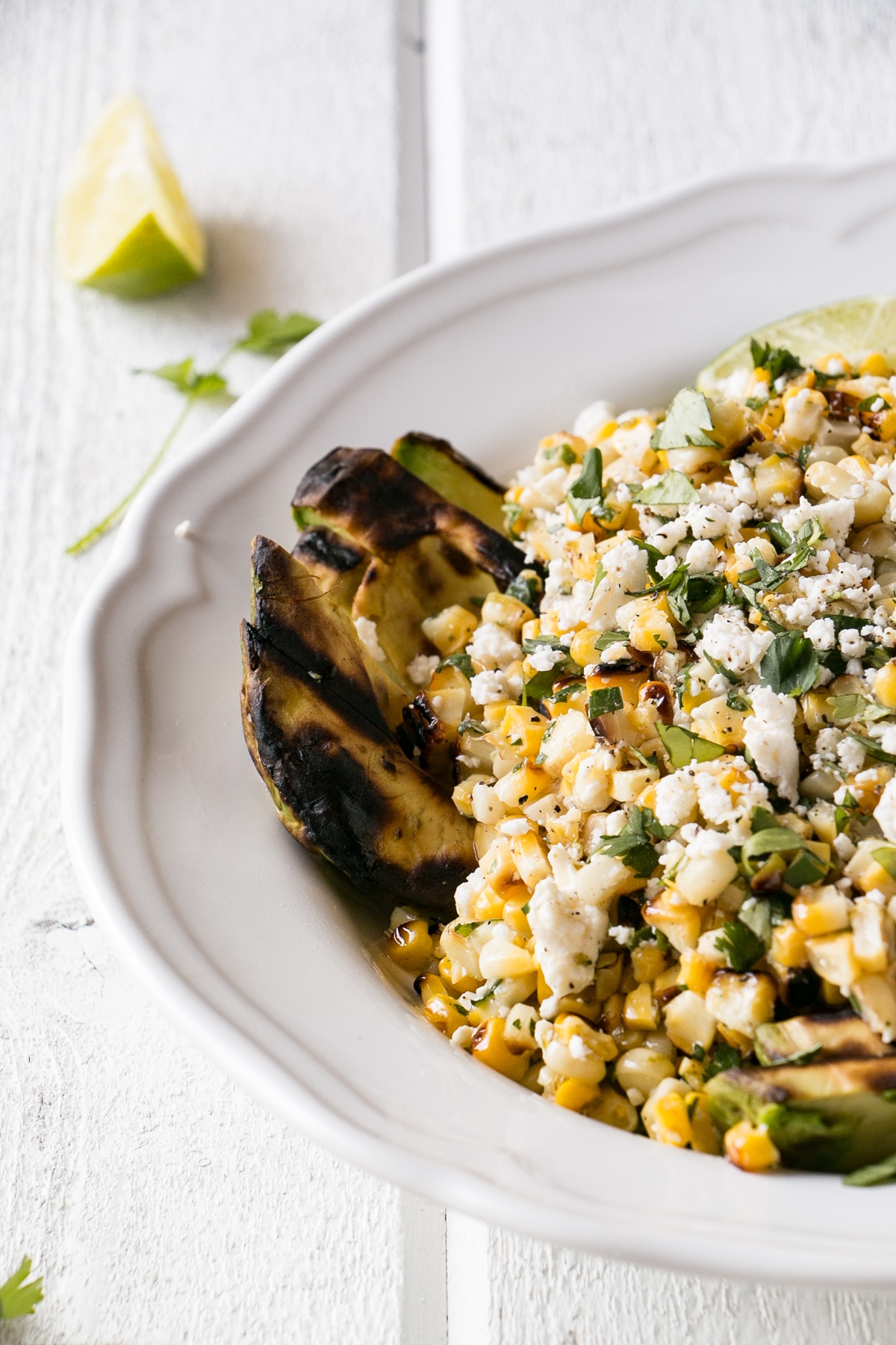 Grilled Corn and Avocado Salad with cilantro and feta cheese in a white serving bowl.
