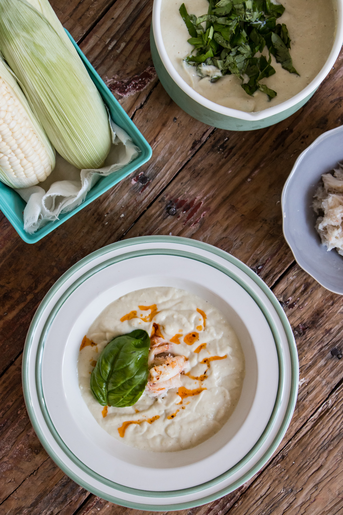 Chilled Corn and Crab Bisque in a white bowl with basil leaf on top