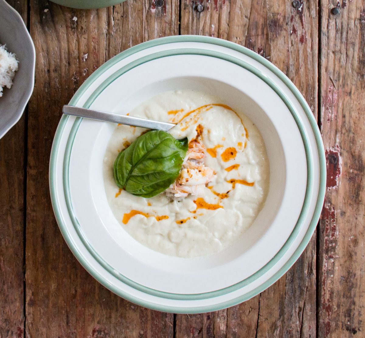 Chilled Corn and Crab Bisque in a white bowl with basil leaf on top