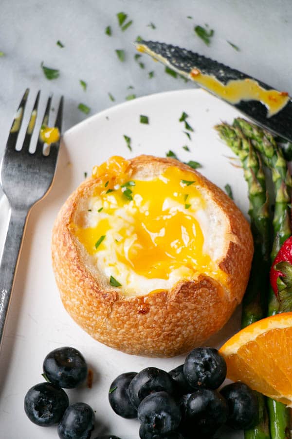 Oven Baked Eggs in Buns with bright berries, oranges, and asparagus.