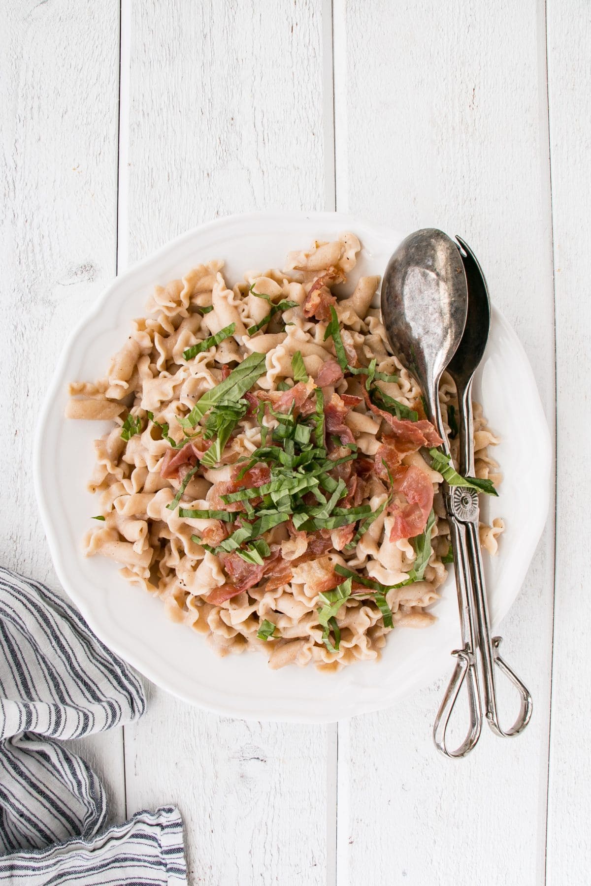 Creamy Garlic Basil Pasta in a serving bowl w/ serving spoons