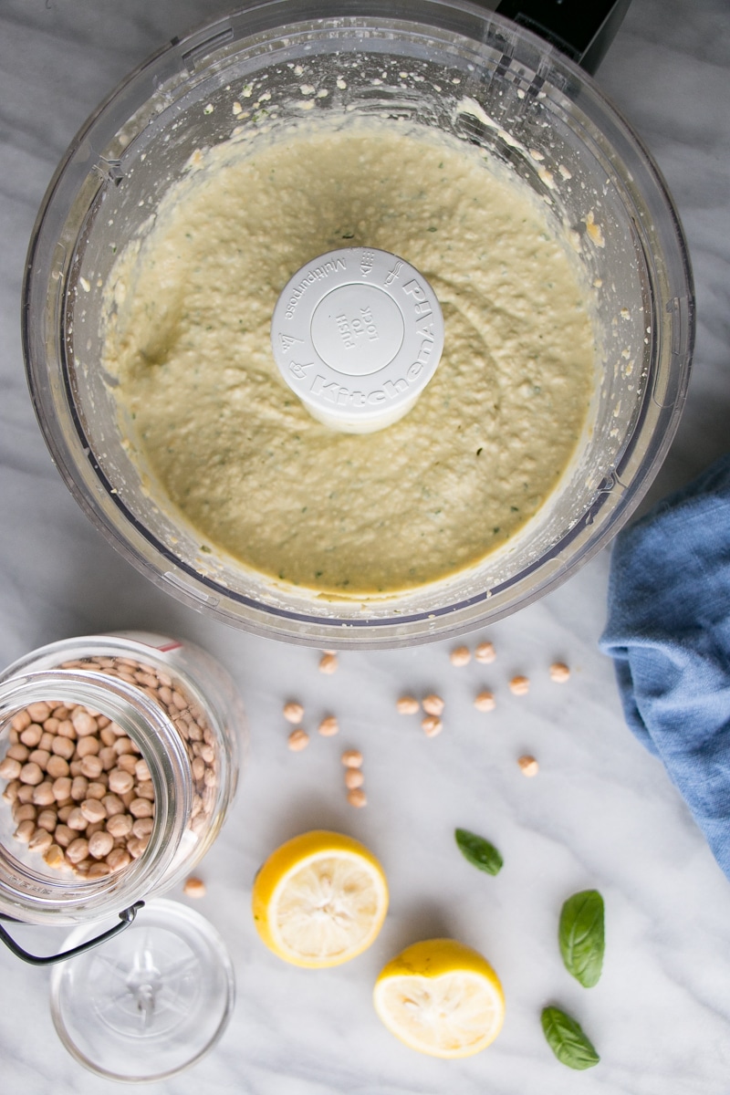 Food processor with a puree of hummus and dried chickpeas and other ingredients. 