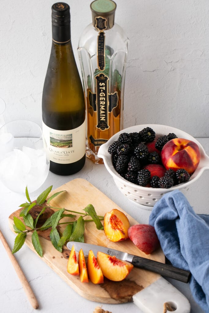 Ingredients laid out for Summer Sangria: white wine, blackberries, peaches, elderflower liquor and fresh mint. 