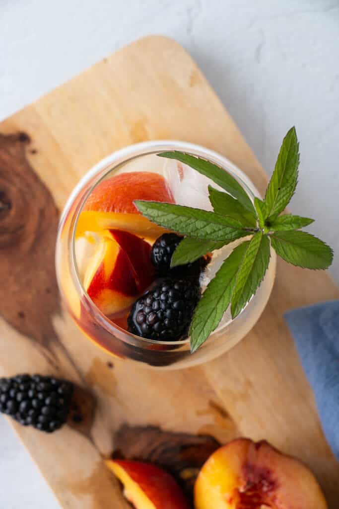 Top down shot of Summer Sangria with ripe deep purple blackberries, deep orange peaches and fresh green mint. 