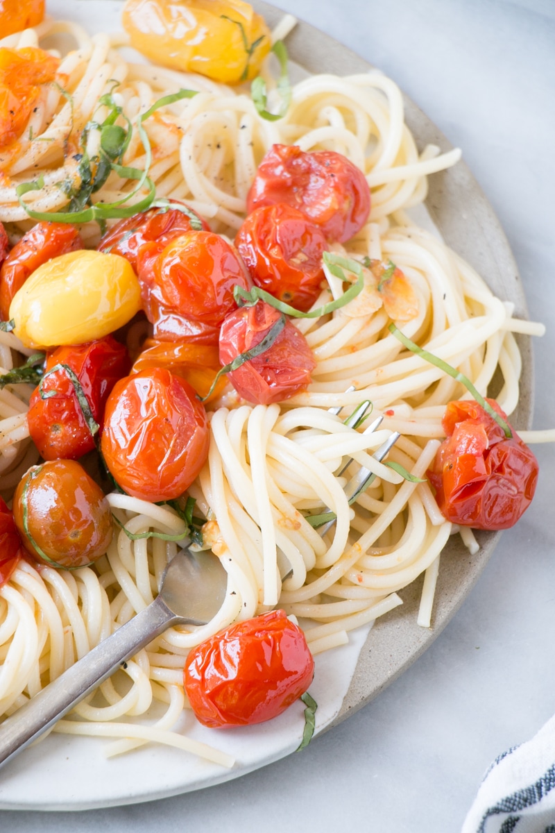 Summer Tomato Basil Pasta with thin long noodles, burst cherry tomatoes, and a big dollop of creamy whipped ricotta cheese.