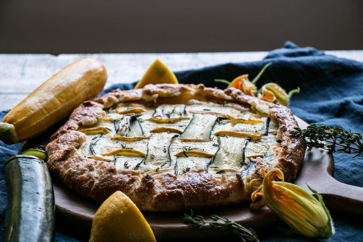 Zucchini Galette on a round wooden board with a blue linen.