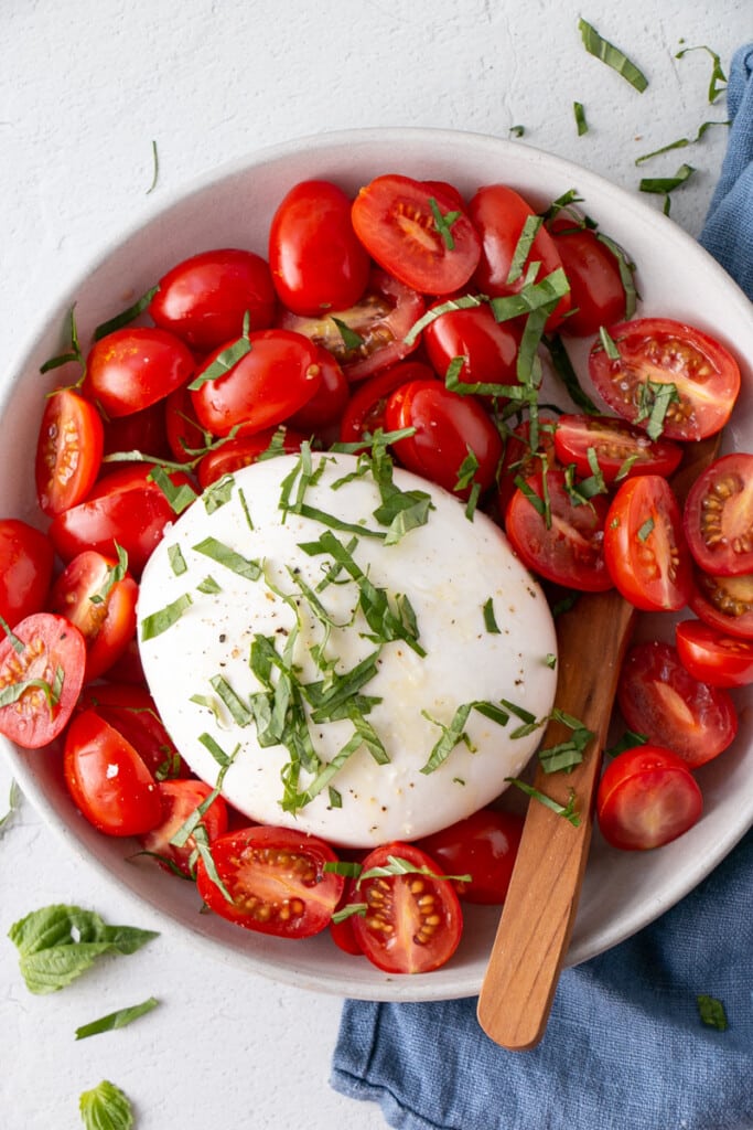 Cherry Tomato Salad with creamy Burrata and topped with thinly sliced fresh basil leaves.