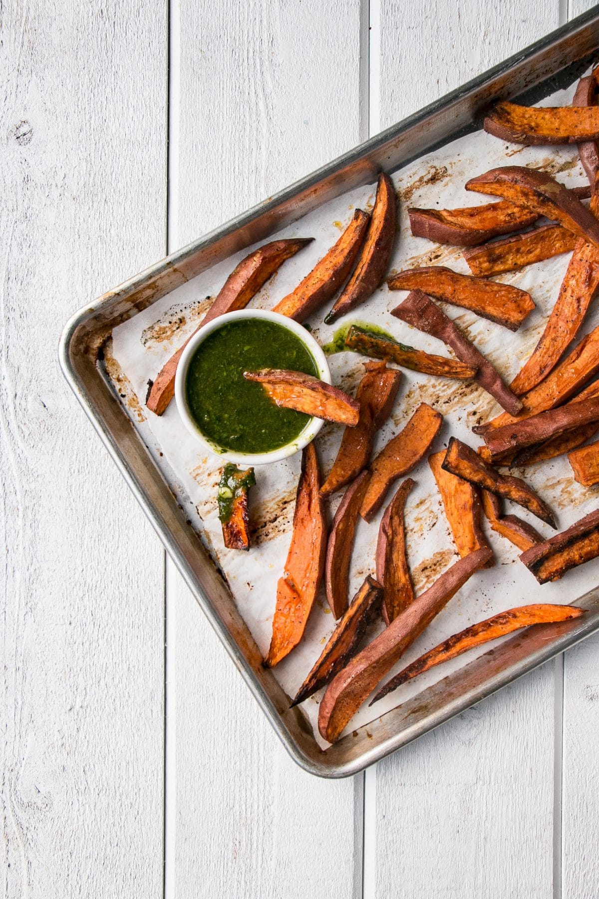Roasted Sweet Potatoes with Chimichurri is a vibrant and delicious side dish! Super healthy with baked sweet potato fries and herb packed chimichurri sauce. #healthy #sweetpotatoes #fries #chimichurri
