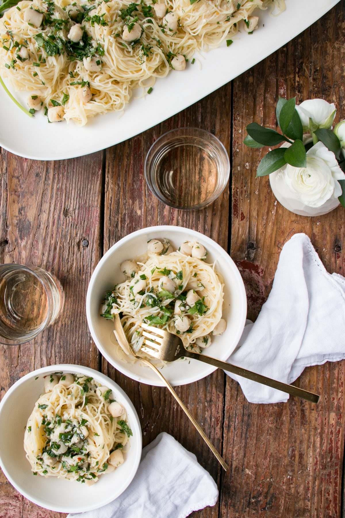 White Wine Butter Scallops over pasta in bowls with a wood background
