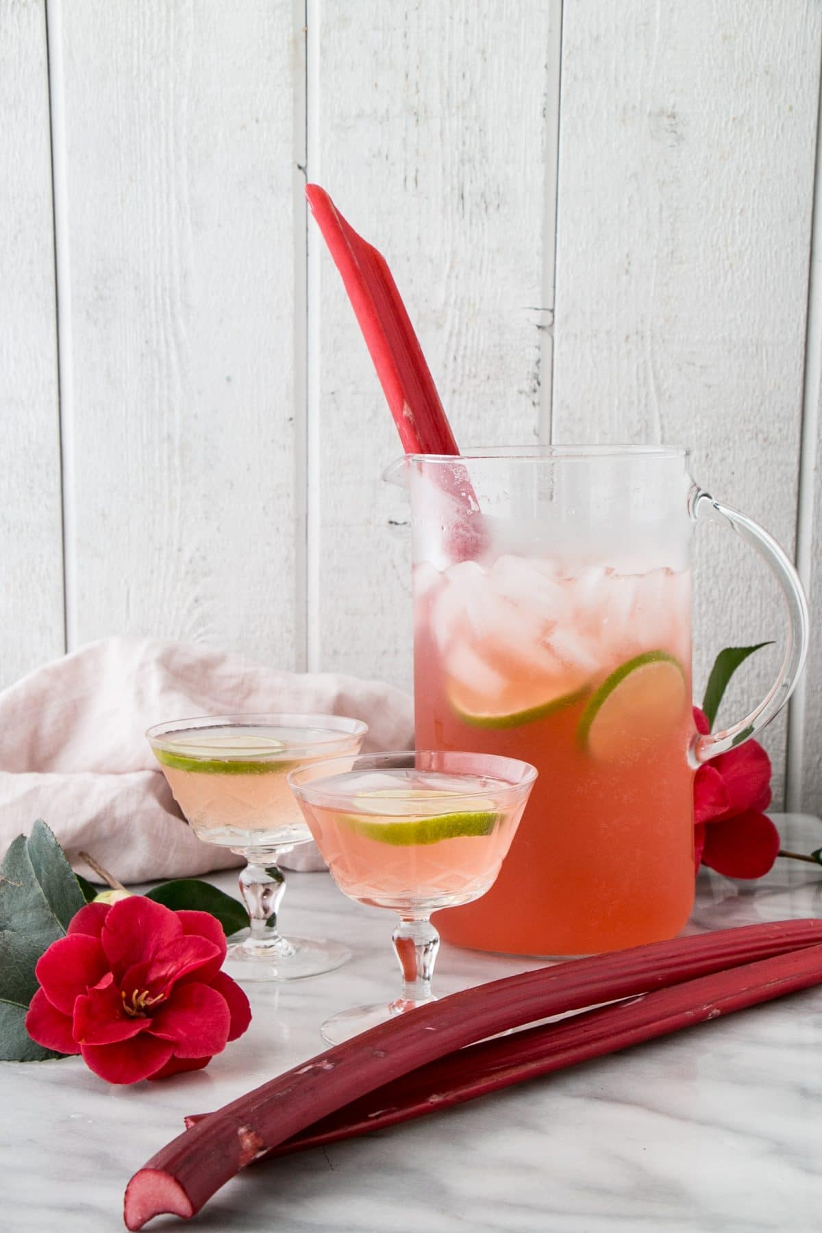 sparkling rhubarb margarita in a pitcher with two glass filled.