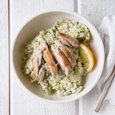 Broccoli and Goat's Cheese Orzo with chicken sliced on top in a white bowl.