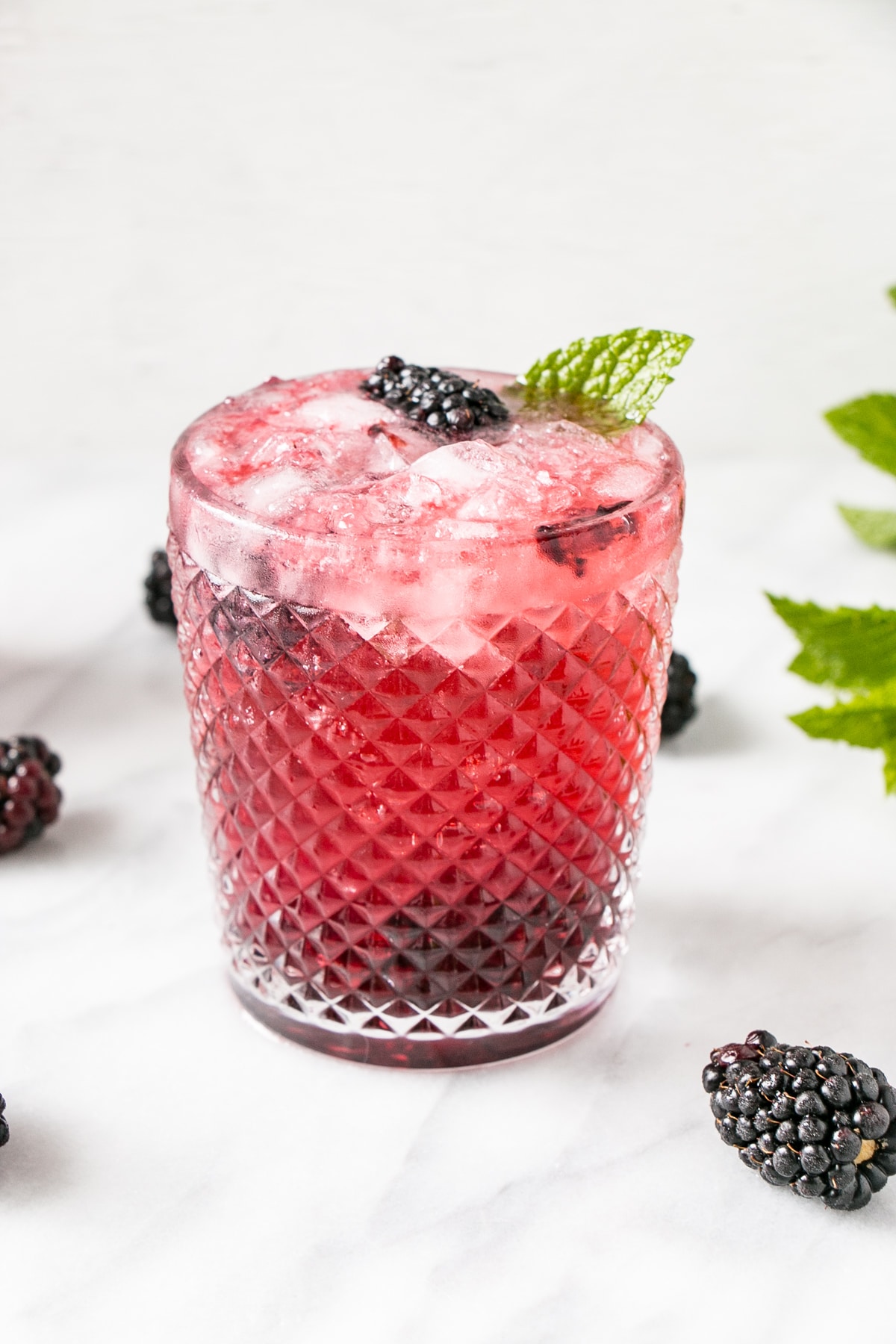 Blackberry Mojito in a textured glass with blackberries, lime and mint.