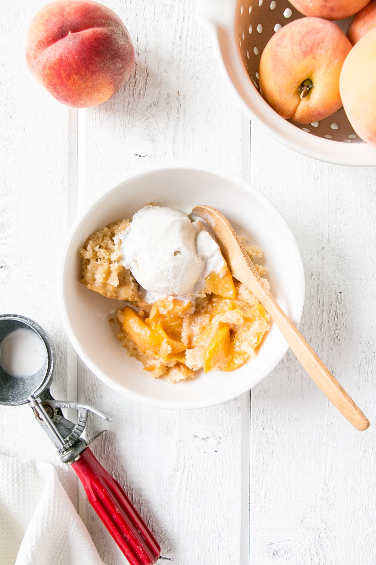 Slow Cooker Peach Cobbler in a white bowl with vanilla ice cream
