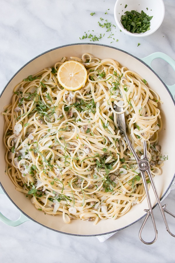 Linguine with Clam Sauce in a large round pot with tongs and a half of a lemon. 
