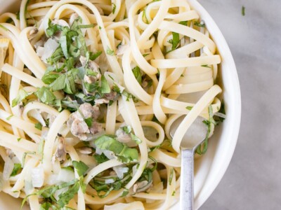 Linguine with Clam Sauce in a white bowl with pasta noodles twirled around the end of a fork.