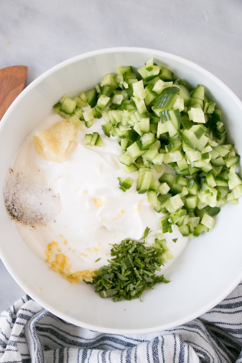 How to make Tzatziki ingredients in a white bowl.