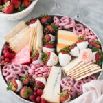 Bright and colourful dessert board with white chocolate and dark chocolate covered strawberries and colourful cheeses.