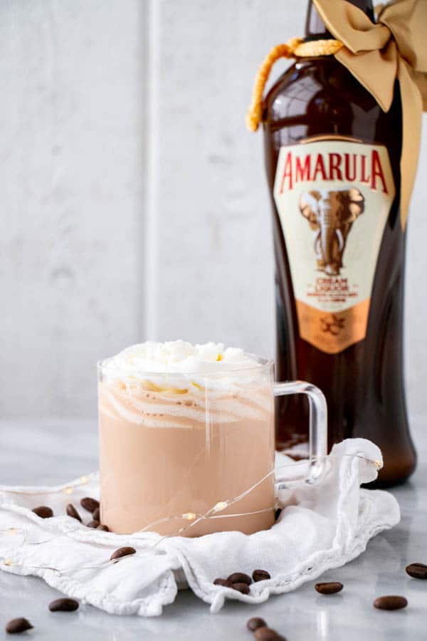 Creamy and decadent Hot White Russian topped with whipped cream in a clear glass mug.