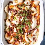 Cheesy Pierogies Casserole with crispy bacon bits and sliced green onion in a white pan.