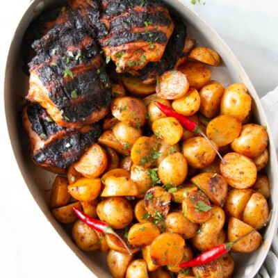 Peri Peri Grilled Chicken and Potatoes in an oval shaped metal dish.