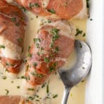 Prosciutto-Wrapped Chicken in a creamy mustard sauce with a scattering of fresh basil on top.