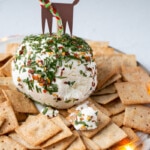 Honey Goat's Cheese Ball with festive drinks and shiny ornaments, surrounding the plate.