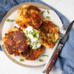 Leftover Crispy golden brown Mashed Potato Pancakes with a big dollop of sour cream and a sprinkling of sliced green onions.