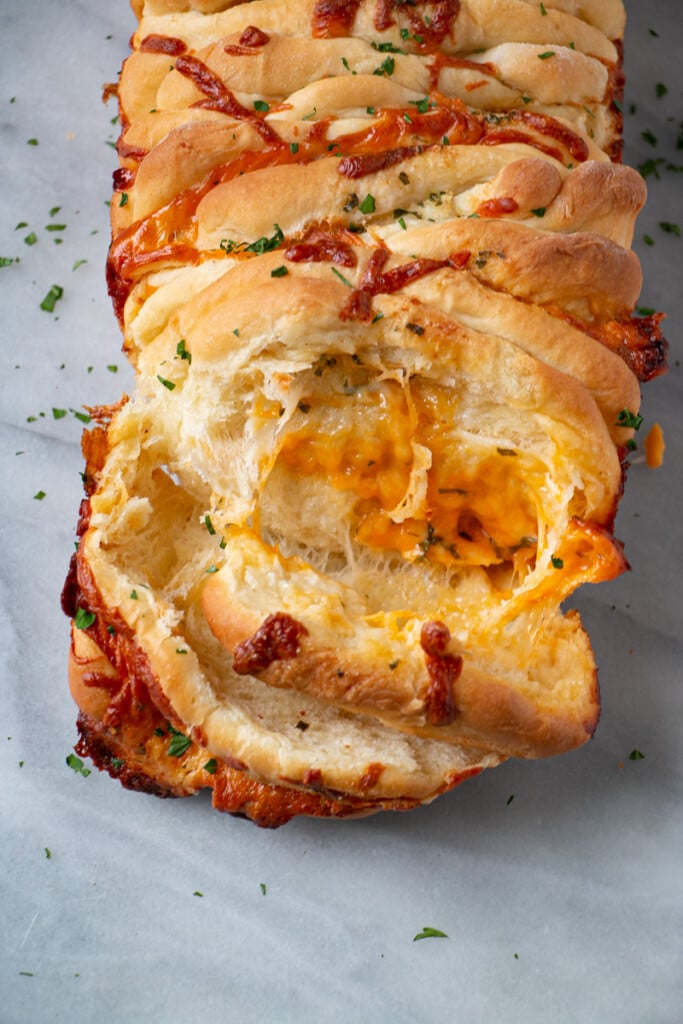Pull Apart Cheese Bread with gooey cheese being pulled between layers shown in a top down shot.