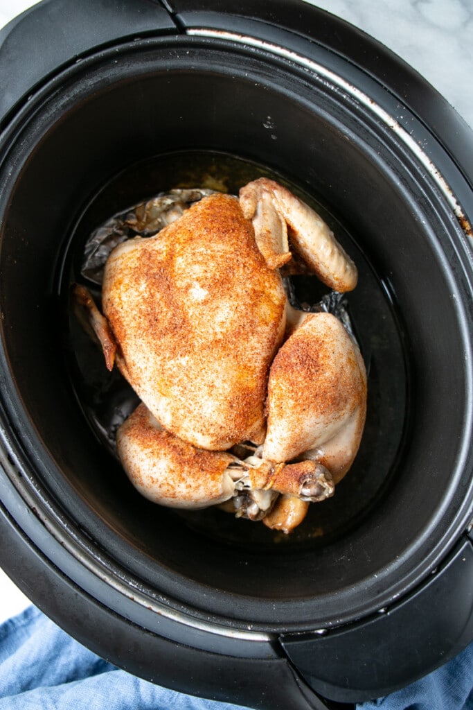 Slow cooker whole chicken with a seasoned rub applied. 